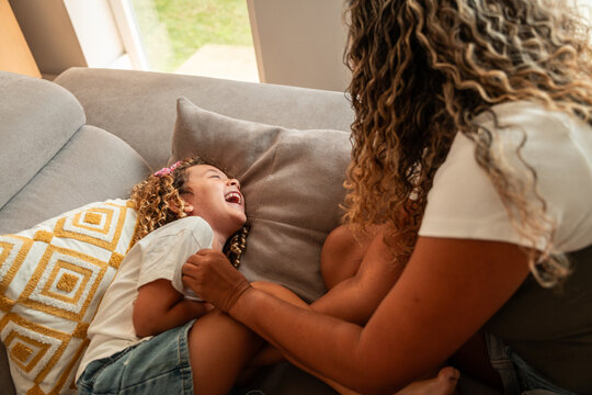 Mother and child laughing together on a cozy sofa at home