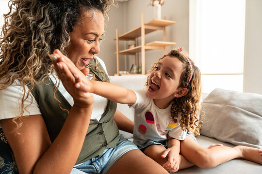 Joyful mother and daughter share a high five at home