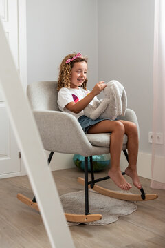 Smiling child hugging plush toy on cozy chair at home