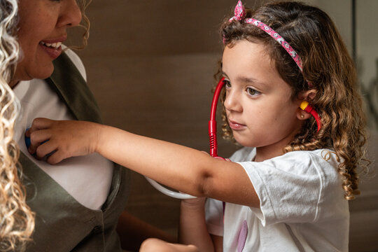 Child playing doctor using stethoscope on pregnant mother