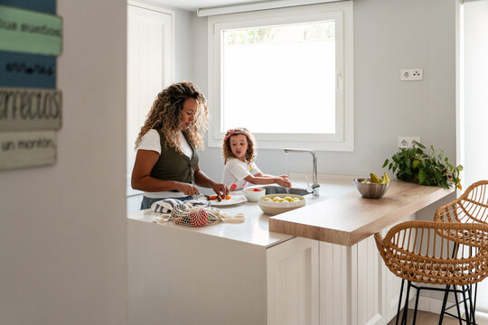 Mother and child preparing fruit together in bright kitchen