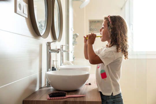 Child brushing teeth at bathroom sink in morning routine