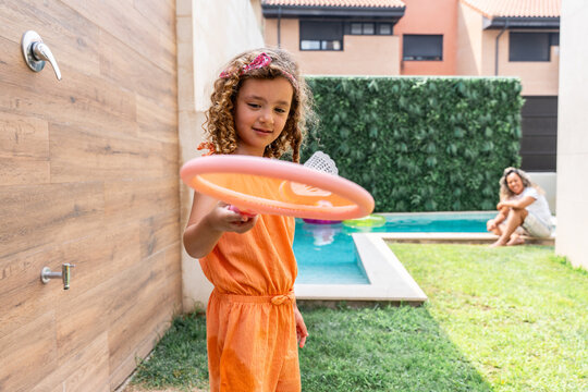 Girl practicing badminton in backyard near swimming pool