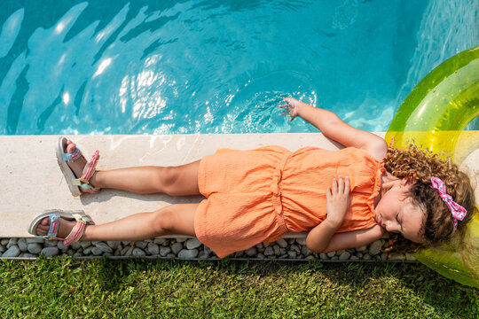 Child resting by pool with inflatable ring on summer day