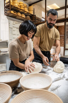 Artisan bakery team shaping dough on floured table