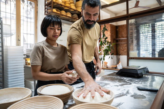 Artisan bakers shaping dough in a small bakery kitchen