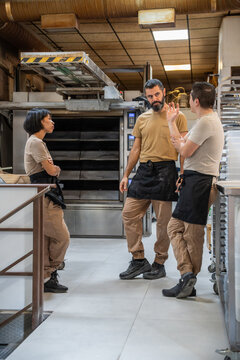 Artisan bakery team meeting in commercial kitchen workspace