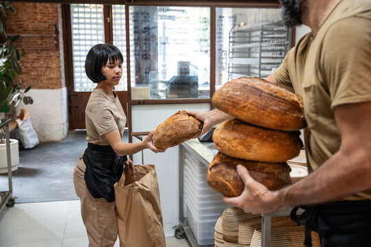 Artisan bakery staff stacking fresh sourdough bread loaves