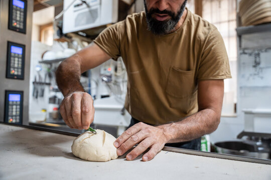 Artisan baker scoring dough on workbench in bakery