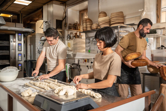 Artisan bakery team shaping dough and handling fresh loaf