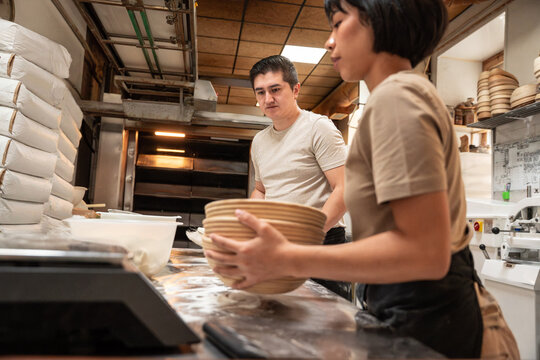 Bakers shaping dough with proofing basket in artisan bakery