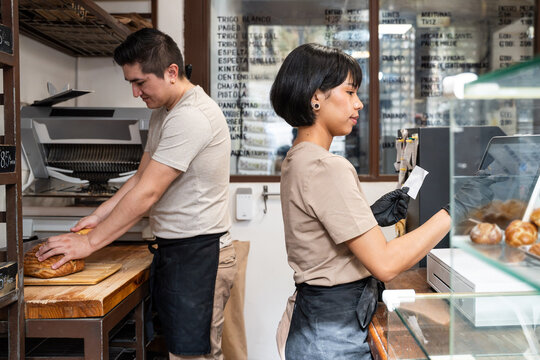 Artisan bakery staff preparing bread and serving customer