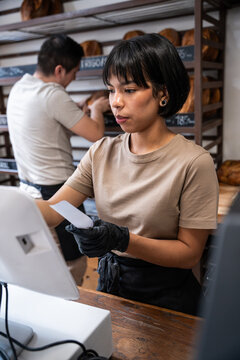 Bakery cashier processing payment in artisan bread shop