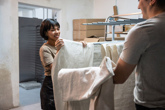 Bakery staff folding linen cloth in artisan bakery workspace