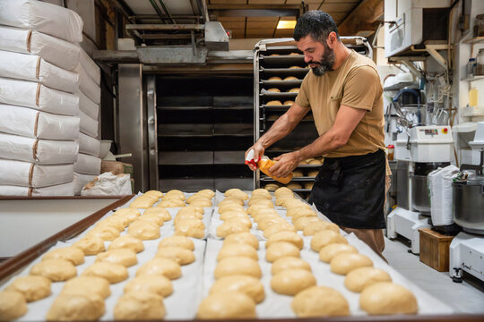 Baker shaping dough on tray in artisan bakery kitchen