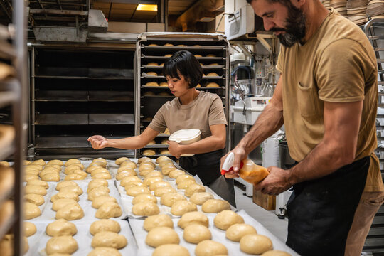 Artisan bakery team prepping dough on trays in kitchen