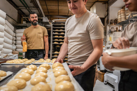Artisan bakery team shaping dough on trays in workshop