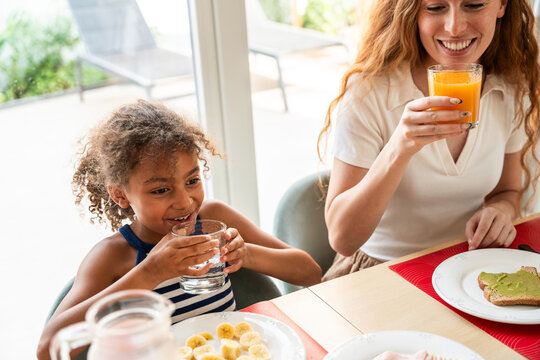 Mother and daughter enjoying breakfast with juice at home
