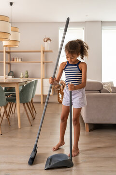 Child sweeping living room floor with dustpan at home
