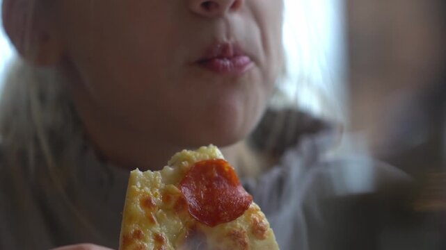 A cute girl eats pizza with her hands in a cafe. A hungry child munches on fast food. A snack at a cafe. High quality FullHD footage