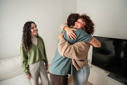 Young adult friend hug in modern living room at home