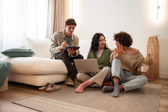 Friends planning at home with laptop and notes on a rug