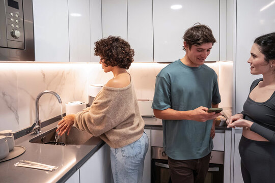Young adult roommate chatting in modern kitchen at home