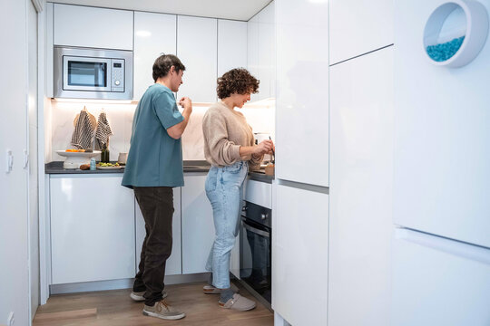 Young couple preparing food together in modern white kitchen
