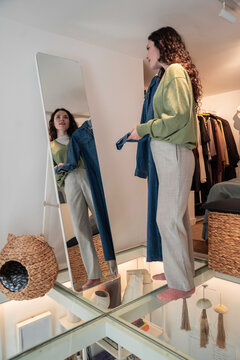 Woman choosing jeans in mirror at home dressing area