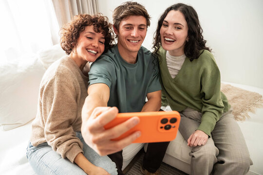 Friends taking a selfie on a sofa in bright home light