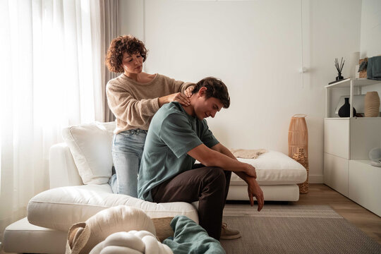 Woman giving neck massage to stressed man at home