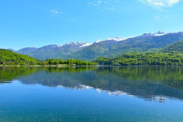 Fototapeta premium View of snow covered peaks in Julian alps above lake Bohinj with a reflection of the mountains in Gorenjska, Slovenia