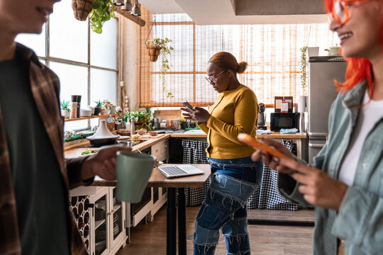 People using smartphone in cozy kitchen with laptop and mug