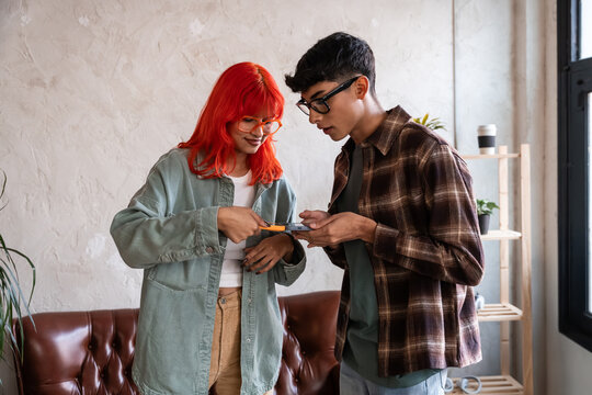Young couple sharing files wirelessly with a smartphone at home