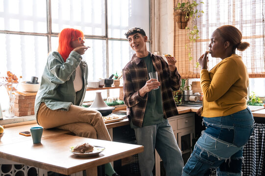 Friends sharing snacks and chatting in a sunny kitchen