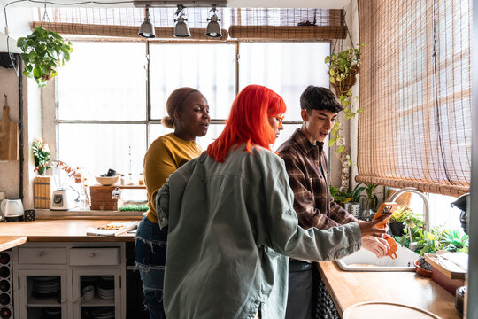 Friends preparing food together in a bright kitchen at home