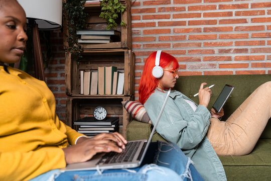 Young woman using tablet with stylus on sofa at home