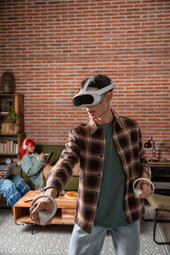 Young man using VR headset and controller in living room