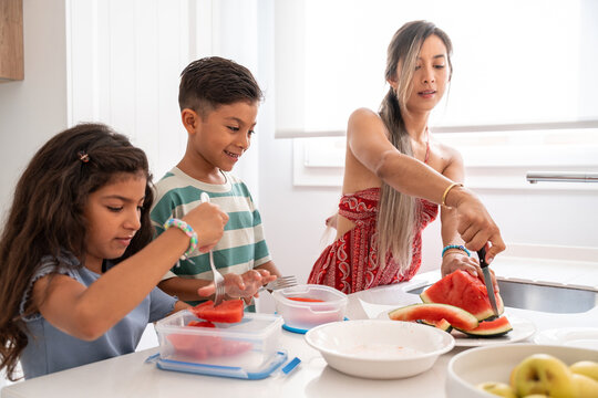 Hispanic family preparing watermelon snack in home kitchen