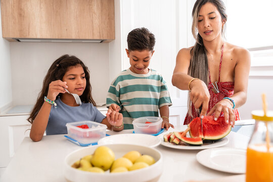 Hispanic family preparing fresh fruit in bright home kitchen