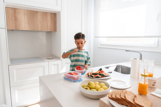 Hispanic family child eating fresh fruit in bright kitchen