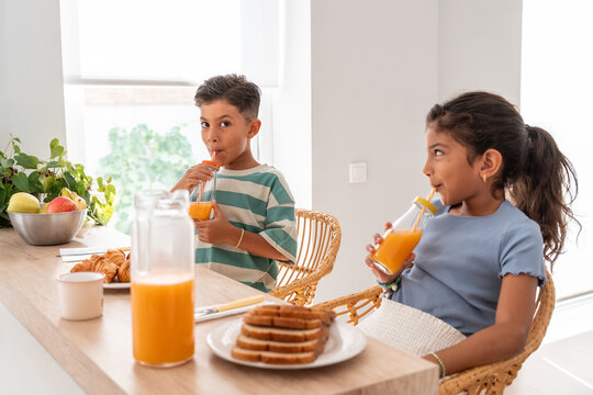 Hispanic family kids drinking orange juice at breakfast