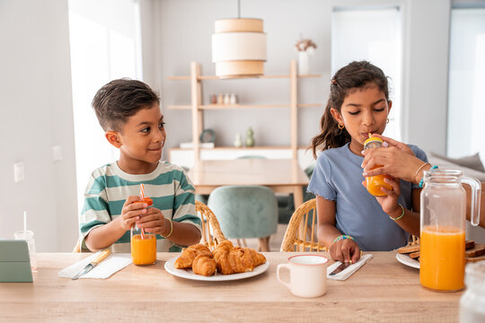 Hispanic family children enjoying breakfast with fresh juice