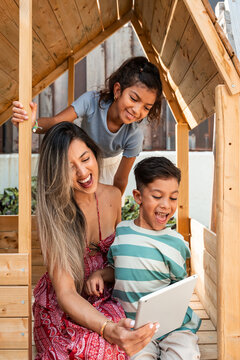 Hispanic mother and children using tablet in playhouse
