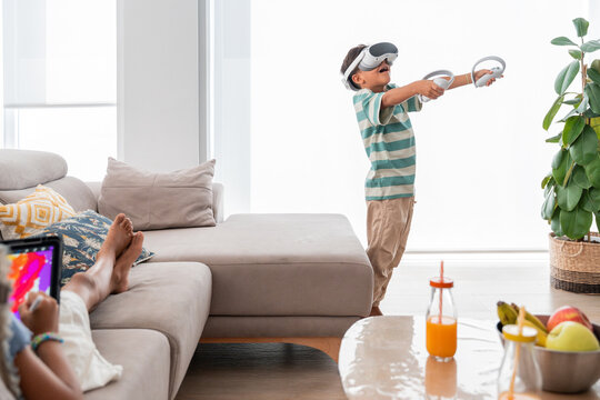 Hispanic kids enjoying tablet and VR play in living room