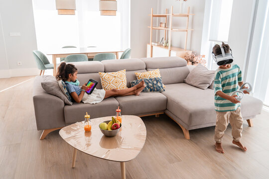 Hispanic kids enjoying tablet and VR play in living room