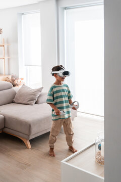 Young hispanic boy using VR headset in bright living room