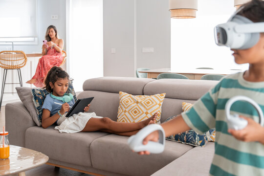 Hispanic family relaxing at home with vr and tablet