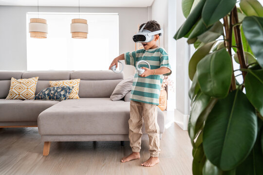 Hispanic boy using VR headset and controllers at home