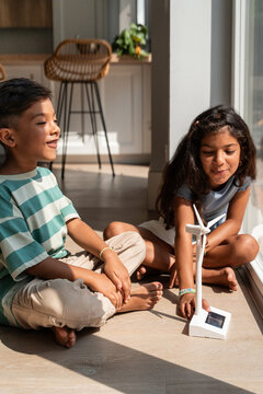 Hispanic siblings learning about wind energy at home